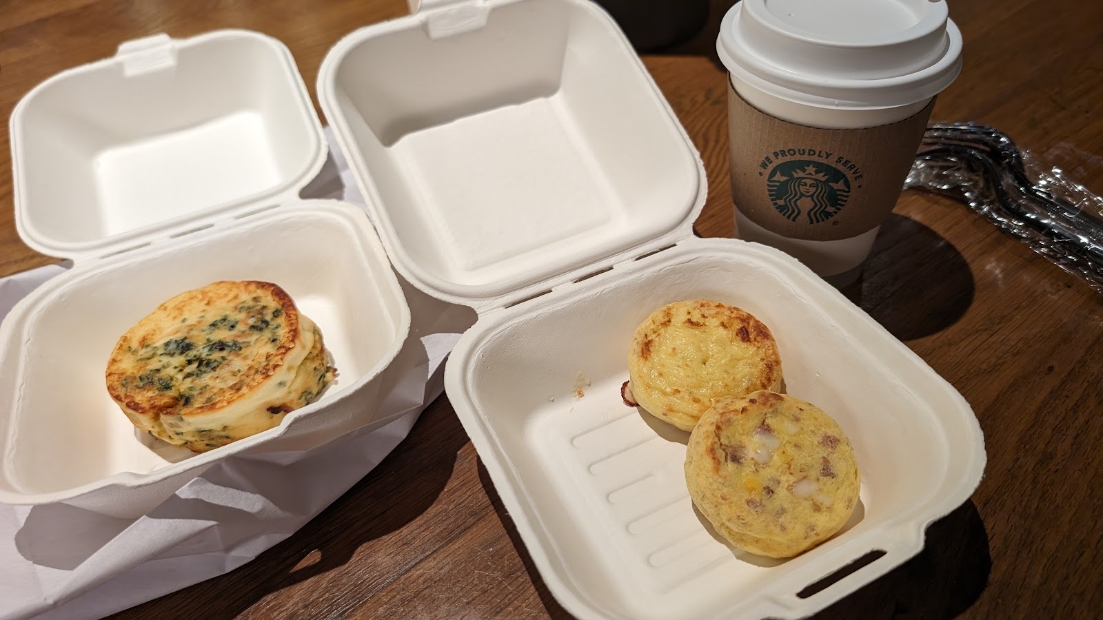 Two open takeout boxes of golden egg frittatas beside a coffee cup.