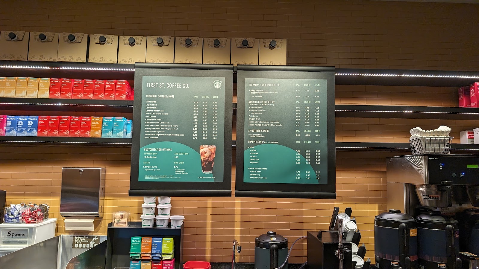 The drink menu boards above the counter, listing espresso drinks, teas, refreshers and frappuccinos with prices.